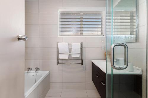 Baño blanco con bañera y lavamanos en Top Spot Rotorua, en Rotorua