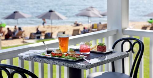a tray of food and drinks on a table on a balcony with the beach at Madison Beach Hotel, Curio Collection by Hilton in Madison