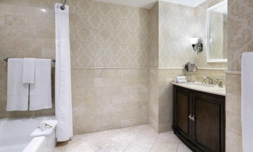 a bathroom with a tub and a sink and a toilet at Madison Beach Hotel, Curio Collection by Hilton in Madison