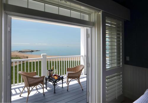 a balcony with two chairs and a table with a view of the ocean at Madison Beach Hotel, Curio Collection by Hilton in Madison