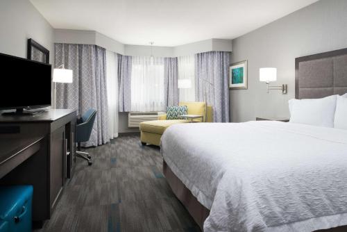 モントレーにあるHampton Inn Montereyのベッド1台、薄型テレビが備わるホテルルームです。