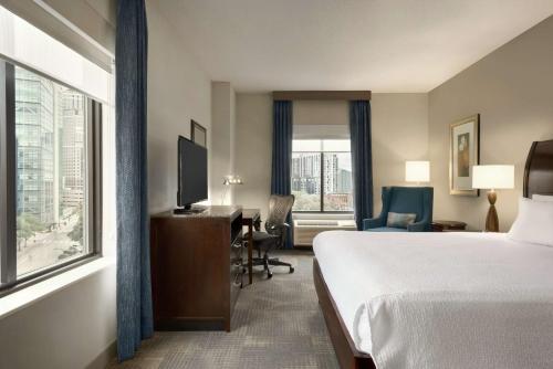 a hotel room with a bed and a desk and a window at Hilton Garden Inn Minneapolis Downtown in Minneapolis