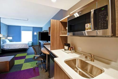 a hotel room with a kitchen with a sink and a bed at Home2 Suites By Hilton Eagan Minneapolis in Eagan