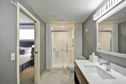 a bathroom with a sink and a toilet and a bed at Home2 Suites By Hilton Minneapolis-Eden Prairie in Minnetonka