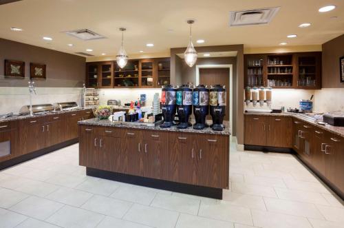 a large kitchen with brown cabinets and a counter with bottles at Homewood Suites by Hilton Minneapolis - Saint Louis Park at West End in Saint Louis Park