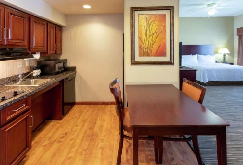 a kitchen with a table and a room with a bed at Homewood Suites by Hilton Minneapolis - Saint Louis Park at West End in Saint Louis Park