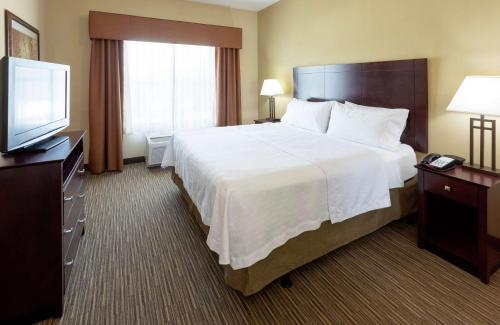 a hotel room with a large bed and a flat screen tv at Homewood Suites by Hilton Minneapolis - Saint Louis Park at West End in Saint Louis Park