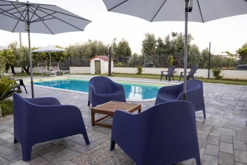 a pool with blue chairs and umbrellas and a table and chairs at Stella Marina - Camere e Monolocali Turistici in Monte San Biagio