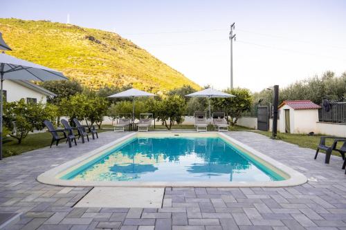 a swimming pool with chairs and a mountain in the background at Stella Marina - Camere e Monolocali Turistici in Monte San Biagio