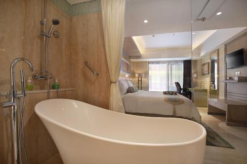 a bathroom with a tub and a bedroom with a bed at SenS Hotel and Spa in Ubud