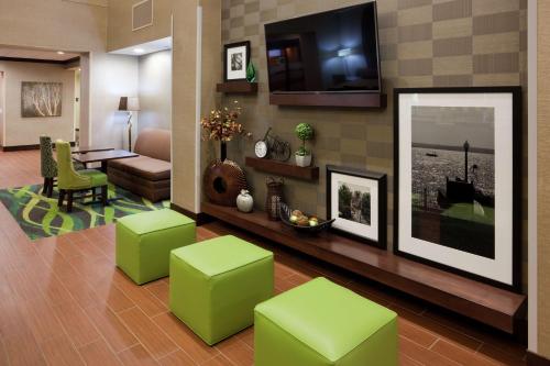 a living room with green stools and a television at Hampton Inn & Suites Minneapolis West/ Minnetonka in Minnetonka
