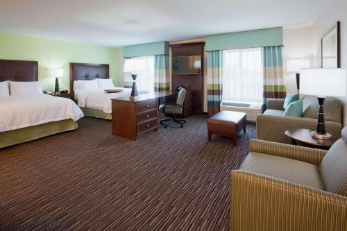 ミネトンカにあるHampton Inn & Suites Minneapolis West/ Minnetonkaのベッド2台、デスク、ソファが備わるホテルルームです。