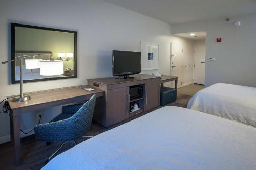 a hotel room with a desk with a television and a bed at Hampton Inn & Suites New Orleans/Elmwood in Harahan