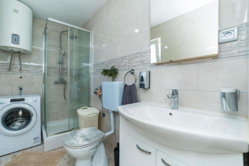 een badkamer met een wastafel en een wasmachine bij Vila Zara in Nin