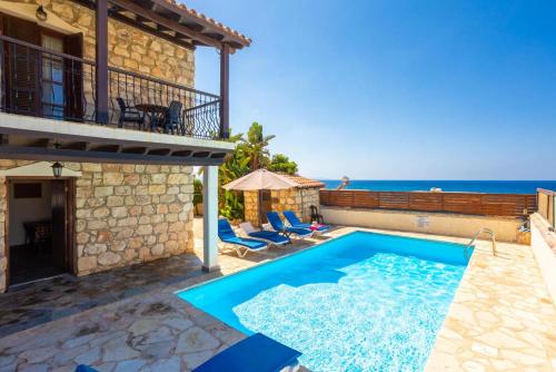 a villa with a swimming pool and the ocean at Villa Petroktisto in Pomos