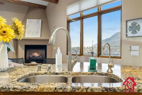 a kitchen counter with a sink and a fireplace at Elena's Sandia Sanctuary - An Irvie Home in Albuquerque