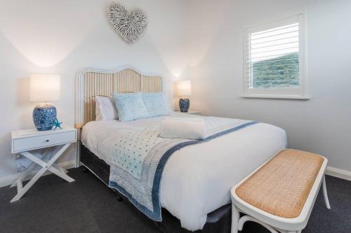 a white bedroom with a large bed and a window at Midd's on the Beach - luxury beach front apartment in Albany
