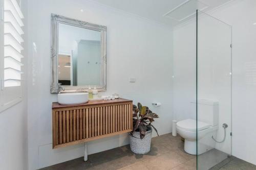 a bathroom with a sink and a mirror and a toilet at Midd's on the Beach - luxury beach front apartment in Albany