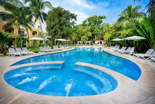 ein großer Pool mit Stühlen und Sonnenschirmen in der Unterkunft Viva Maya by Wyndham, A Trademark All Inclusive Resort in Playa del Carmen