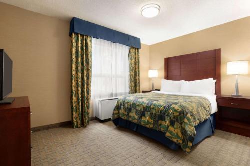 a hotel room with a bed and a window at Travelodge by Wyndham Oshawa Whitby in Oshawa