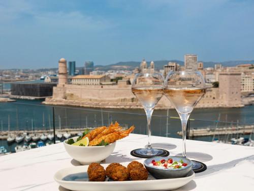 two glasses of wine and a plate of food on a table at Sofitel Marseille Vieux-Port in Marseille