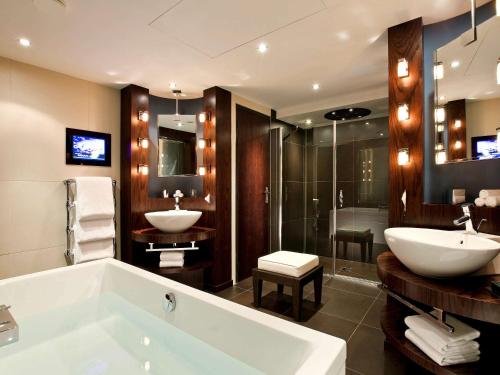 La salle de bains est pourvue d'une baignoire, d'un lavabo et d'une douche. dans l'établissement Sofitel Marseille Vieux-Port, à Marseille