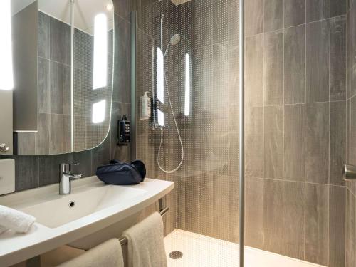 La salle de bains est pourvue d'une douche, d'un lavabo et d'un miroir. dans l'établissement ibis Hotel Brussels off Grand'Place, à Bruxelles