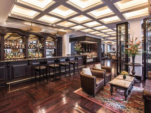 a lobby with a bar with leather chairs and tables at Sofitel Legend Metropole Hanoi in Hanoi
