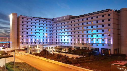 un grand bâtiment avec des lumières bleues au-dessus dans l'établissement Sofitel Athens Airport, à Athènes