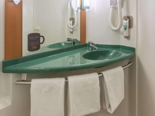 a bathroom with a green sink and towels at ibis Besançon Centre la City in Besançon