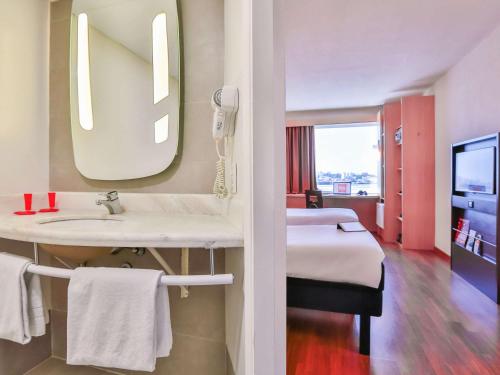 baño con lavabo y cama con espejo en ibis Sao Paulo Congonhas, en São Paulo