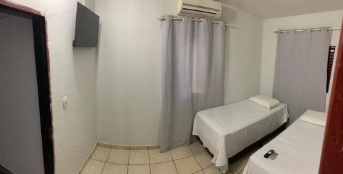 a small bedroom with a bed and a shower at Cerrado Plaza Hotel -dourados in Dourados