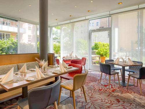 a restaurant with tables and chairs and windows at Mercure Hotel Berlin City in Berlin