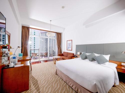 a bedroom with a large white bed and a living room at Novotel Nha Trang in Nha Trang