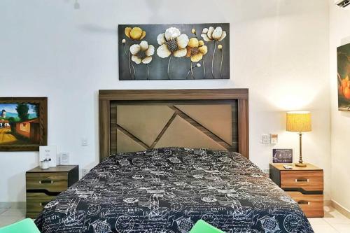 1 dormitorio con 1 cama y una pintura en la pared en Depto Perla a 5 mins de playa con alberca y wifi, en Cabo San Lucas
