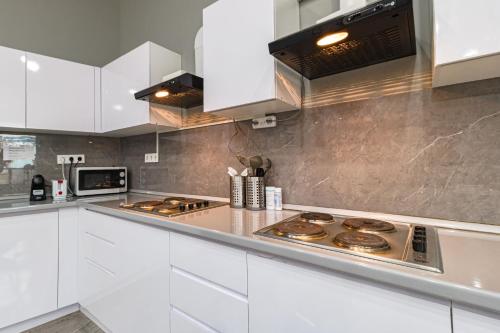 a kitchen with white cabinets and a stove top oven at CAPS LOCK Future Hotel in Astana