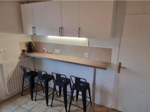 a kitchen with a counter with four chairs around it at L'auberge Angevine in Angers