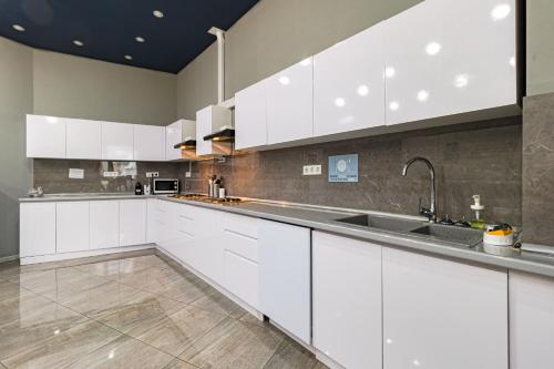 a kitchen with white cabinets and a sink at CAPS LOCK Future Hotel in Astana