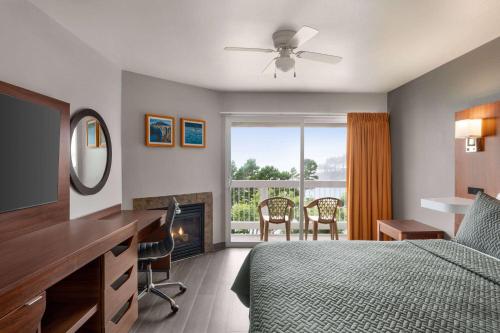 a bedroom with a bed and a desk and a fireplace at Travelodge by Wyndham Depoe Bay in Depoe Bay