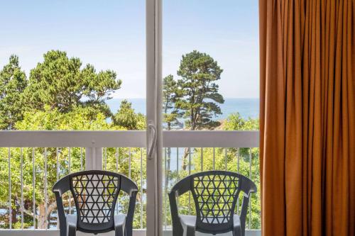 two chairs sitting on a balcony looking out at the ocean at Travelodge by Wyndham Depoe Bay in Depoe Bay