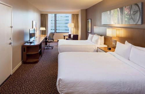 a hotel room with two beds and a desk at Hilton Garden Inn Downtown Dallas in Dallas