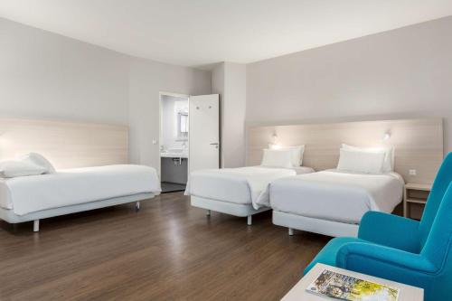 a hotel room with two beds and a blue chair at NH City Centre Amsterdam in Amsterdam