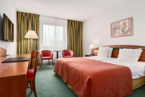 um quarto de hotel com uma cama, uma mesa e cadeiras em NH Maastricht em Maastricht