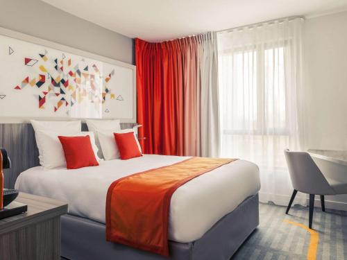 1 dormitorio con 1 cama grande con cortinas rojas y escritorio en Mercure Toulouse Sud, en Toulouse