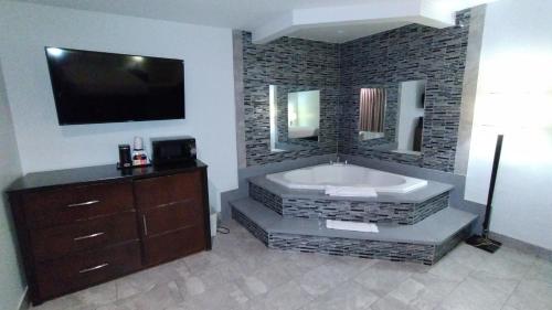 a bathroom with a large tub with a tv on the wall at Baymont by Wyndham Ontario in Ontario