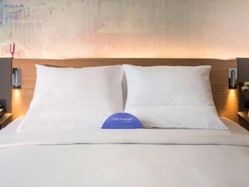 a bed with white pillows and a blue ball on it at Novotel Bangkok Sukhumvit 4 in Bangkok