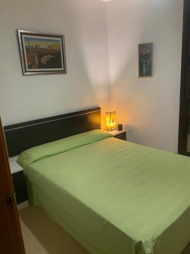 1 dormitorio con 1 cama verde grande con lámpara en Habitación privada, en Calafell