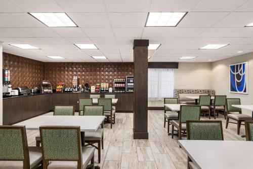 a dining room with tables and chairs and a counter at Wingate by Wyndham Savannah I-95 North in Port Wentworth