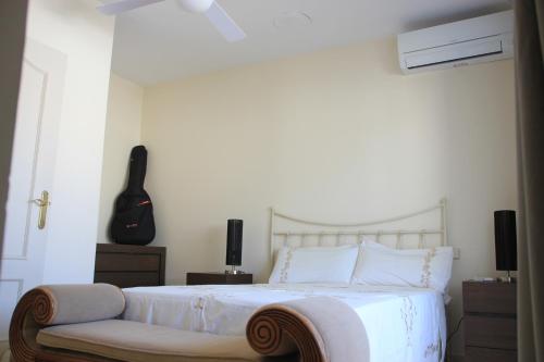 una camera da letto con un letto con una chitarra appesa al muro di Chalet adosado en urbanización con piscina a Estepona