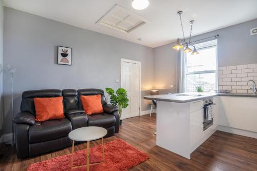 a living room with a black leather couch and a kitchen at 1Bed-Town Centre-Free Parking in Fife